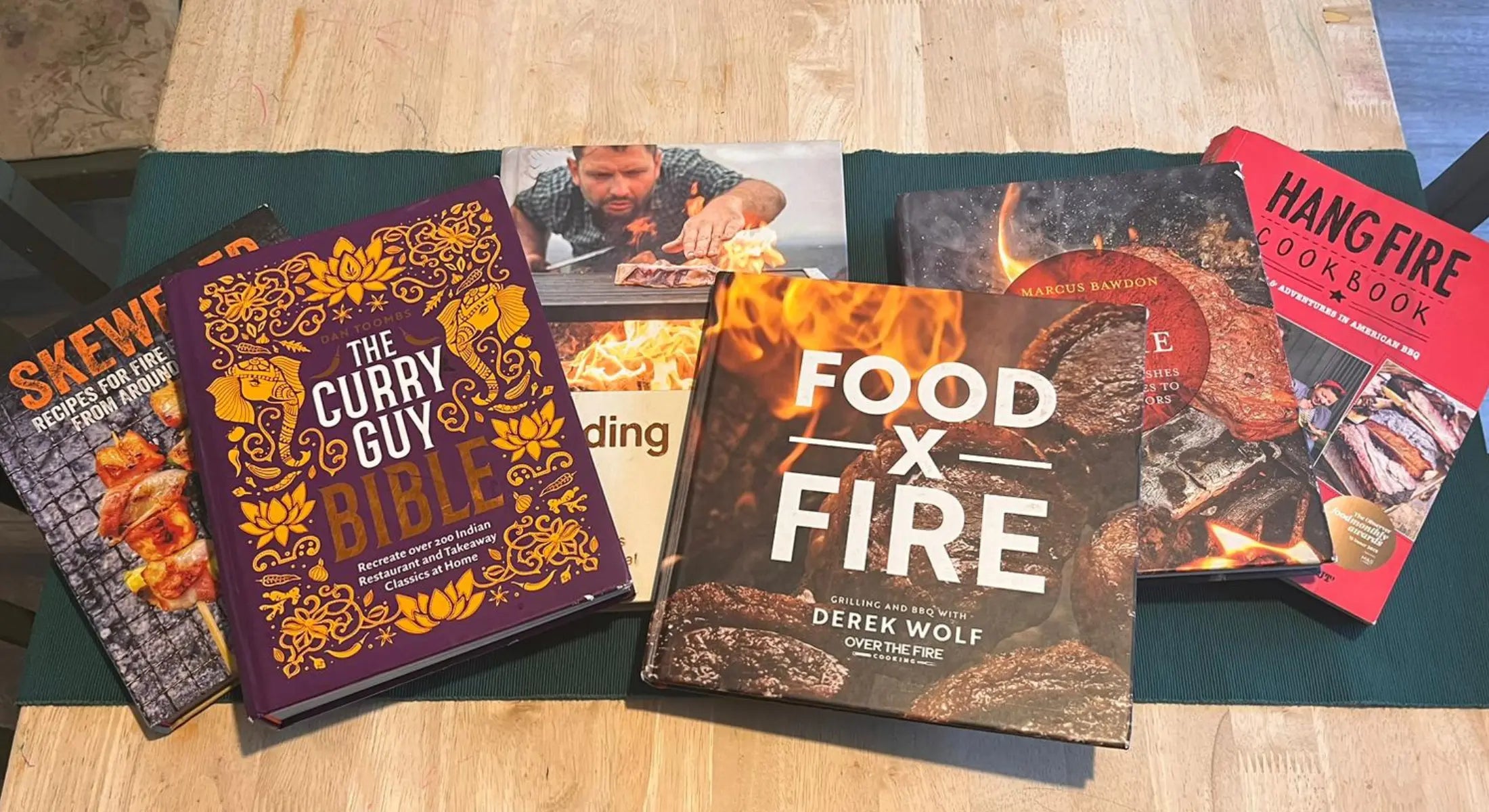 Collection of colourful cookery books focused on wood fired cooking and grilling recipes