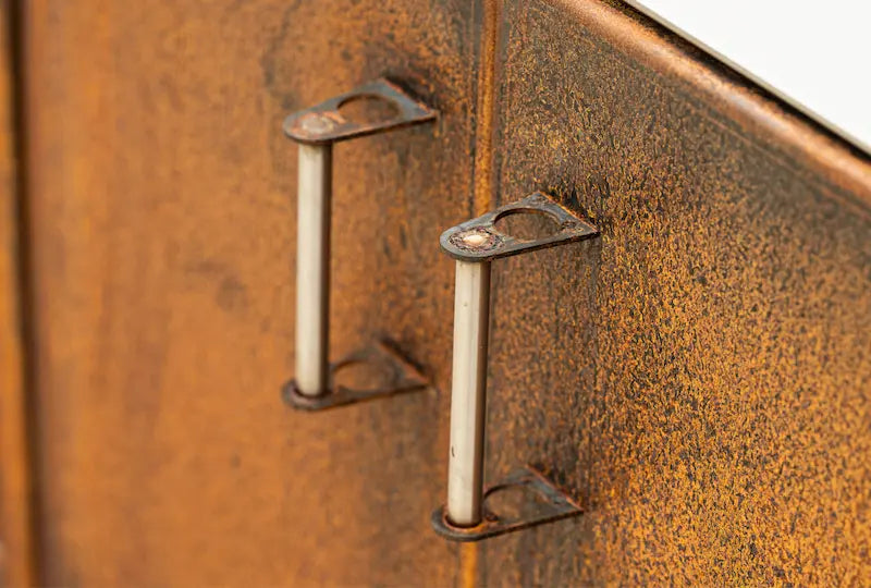 Close-up of rust-coloured Cor-Ten steel worktop unit doors with metal handles