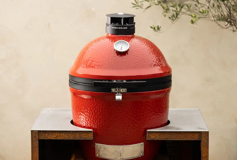 Classic red Kamado Joe ceramic grill with black vent and Cor-Ten steel stand