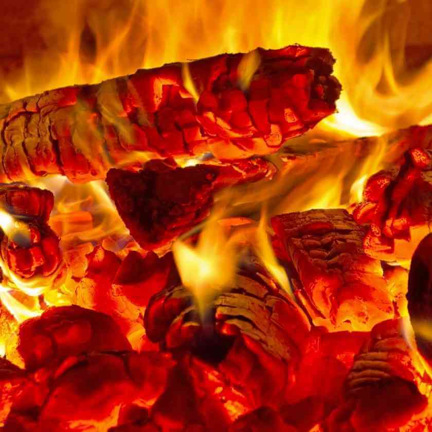 Glowing red hot embers and bright yellow flames in a burning fire