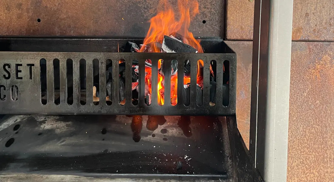 Burning charcoal with bright orange flames inside a black metal Somerset grill