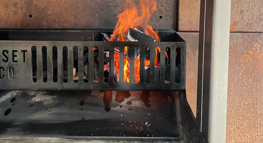 Burning charcoal with bright orange flames inside a black metal Somerset grill