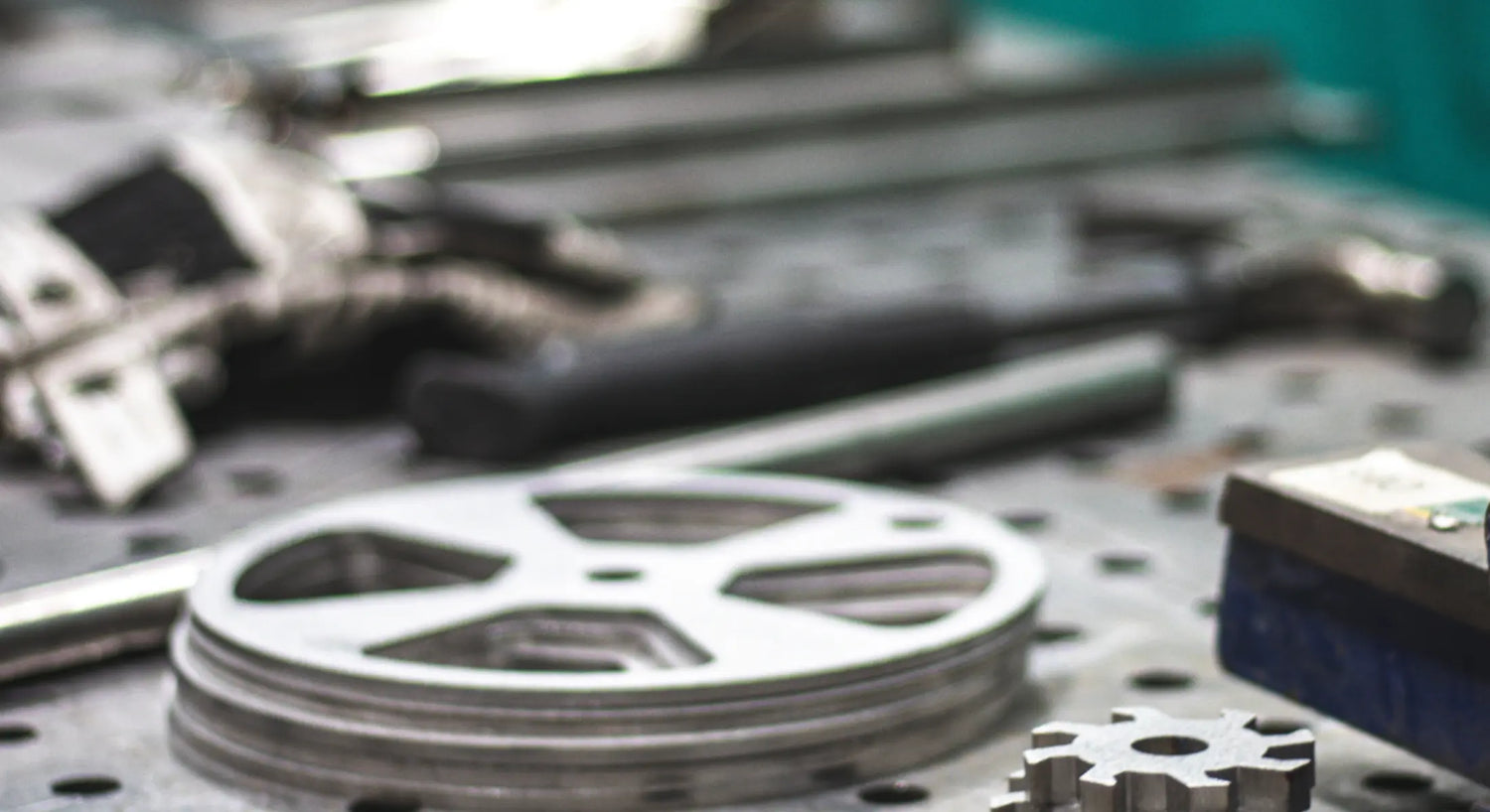 Stack of silver metal circular grill parts with tools on a perforated workbench