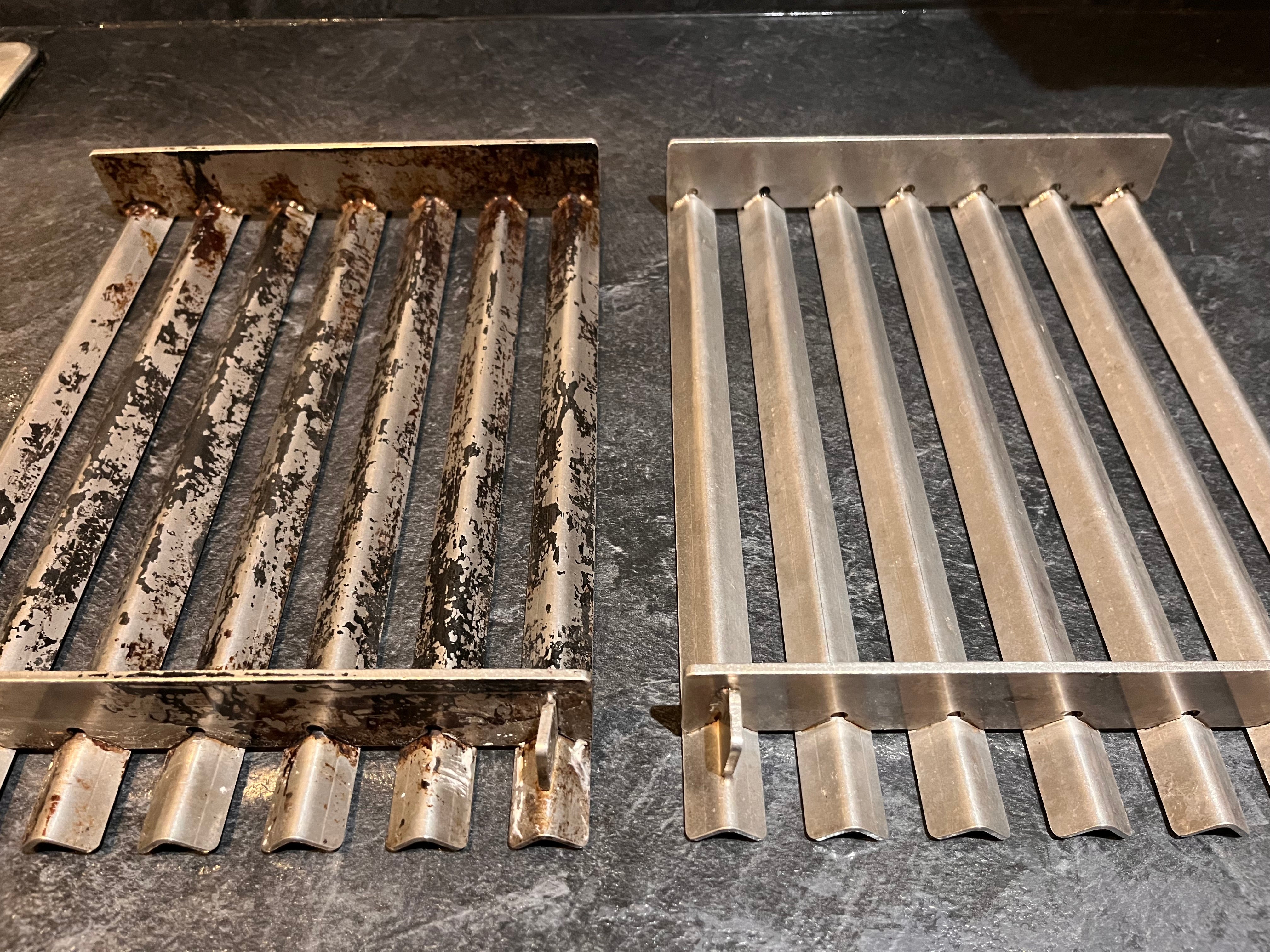 Two V-shaped stainless steel grill plates side by side, one heavily used and dirty, the other clean and polished