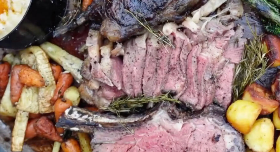Fire-cooked sliced roast elk with roasted carrots, parsnips, potatoes, and fresh herbs
