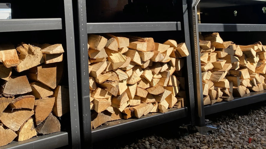 Stacks of split firewood logs neatly arranged on black metal shelves outdoors