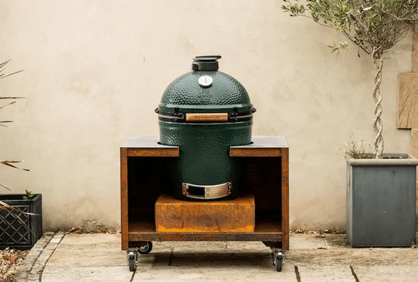 Large green ceramic Big Green Egg barbecue on a rust-coloured Cor-Ten steel stand with wheels