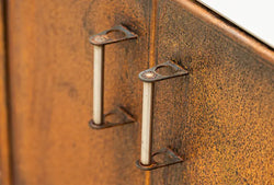 Close-up of rust-coloured Cor-Ten steel worktop unit doors with metal handles